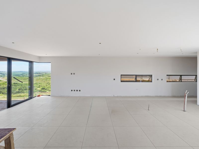 Spacious, light-filled open-plan living area featuring large format floor tiles, expansive sliding glass doors, and panoramic countryside views.