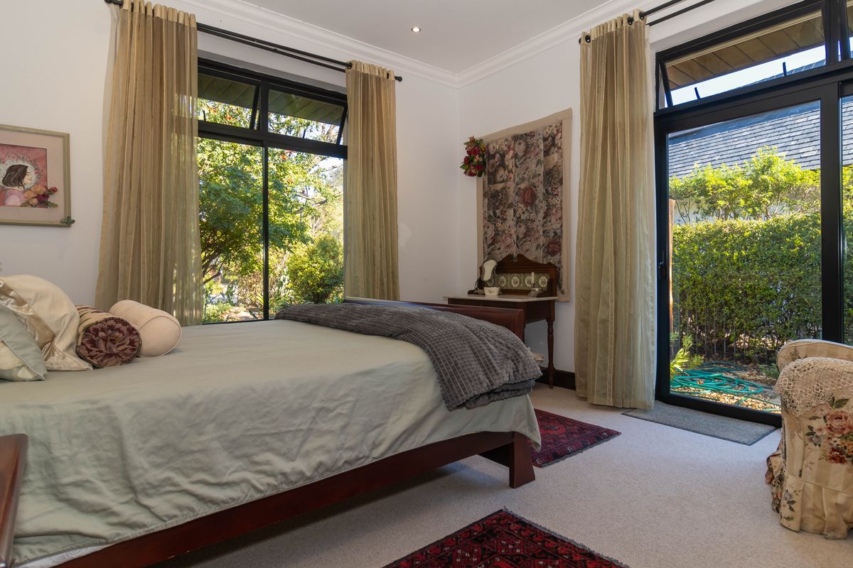 A well-maintained bedroom featuring large black-framed windows and a sliding door providing direct access to the garden.