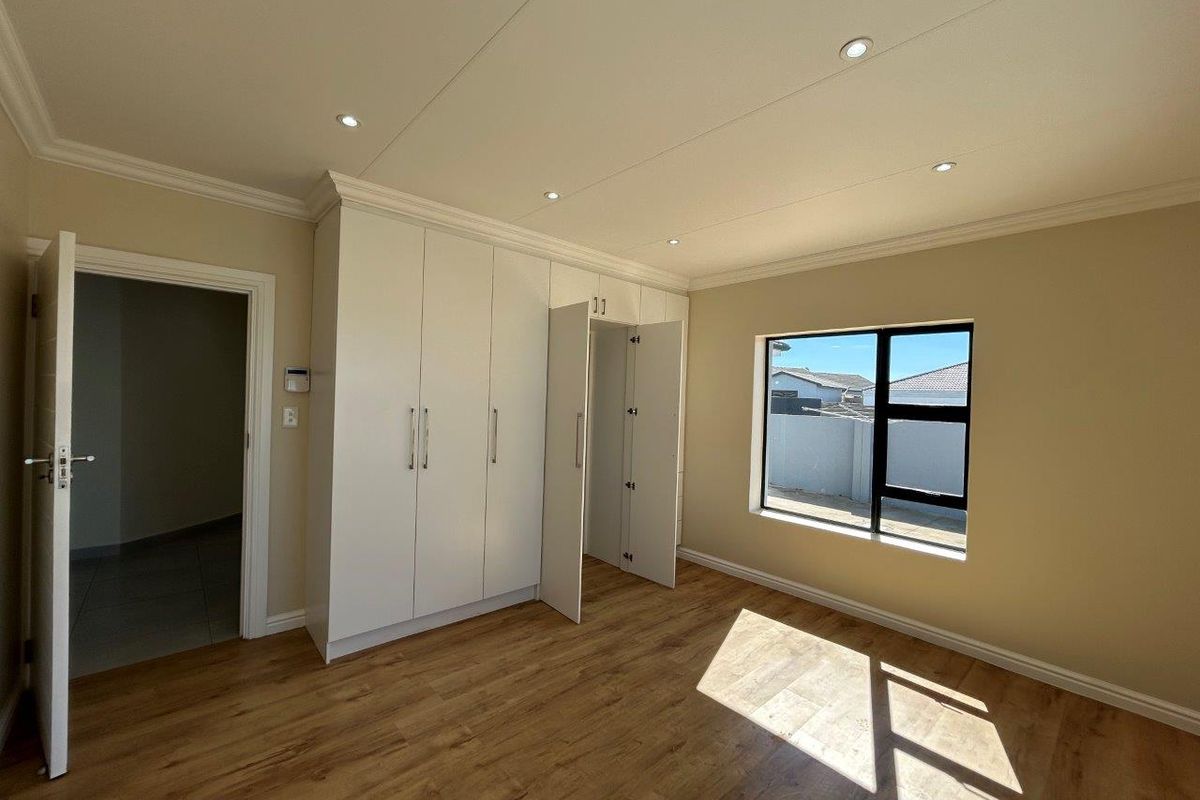 A bright bedroom featuring wood-look flooring, recessed ceiling lighting, and built-in white cabinetry with ample storage space.