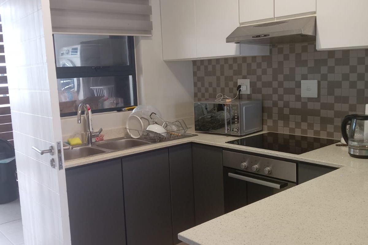 A compact, modern kitchen featuring two-tone cabinetry, stone-look countertops, a built-in oven, hob, and extractor fan with a tiled backsplash.