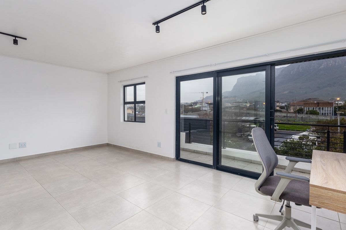 Bright and spacious living area featuring large sliding glass doors that open to a balcony with scenic mountain views and modern tiled flooring.