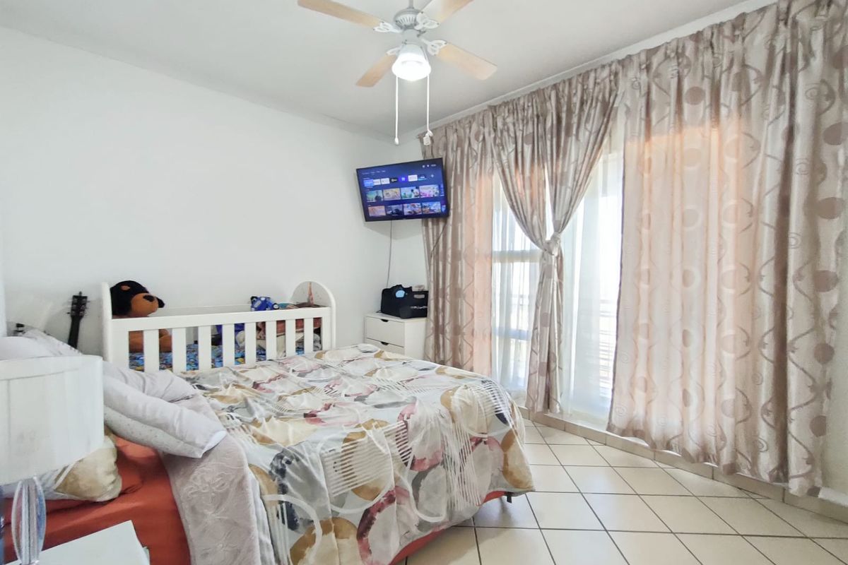 A bedroom featuring tiled flooring, a ceiling fan, and sliding glass doors that provide access to an outdoor area.