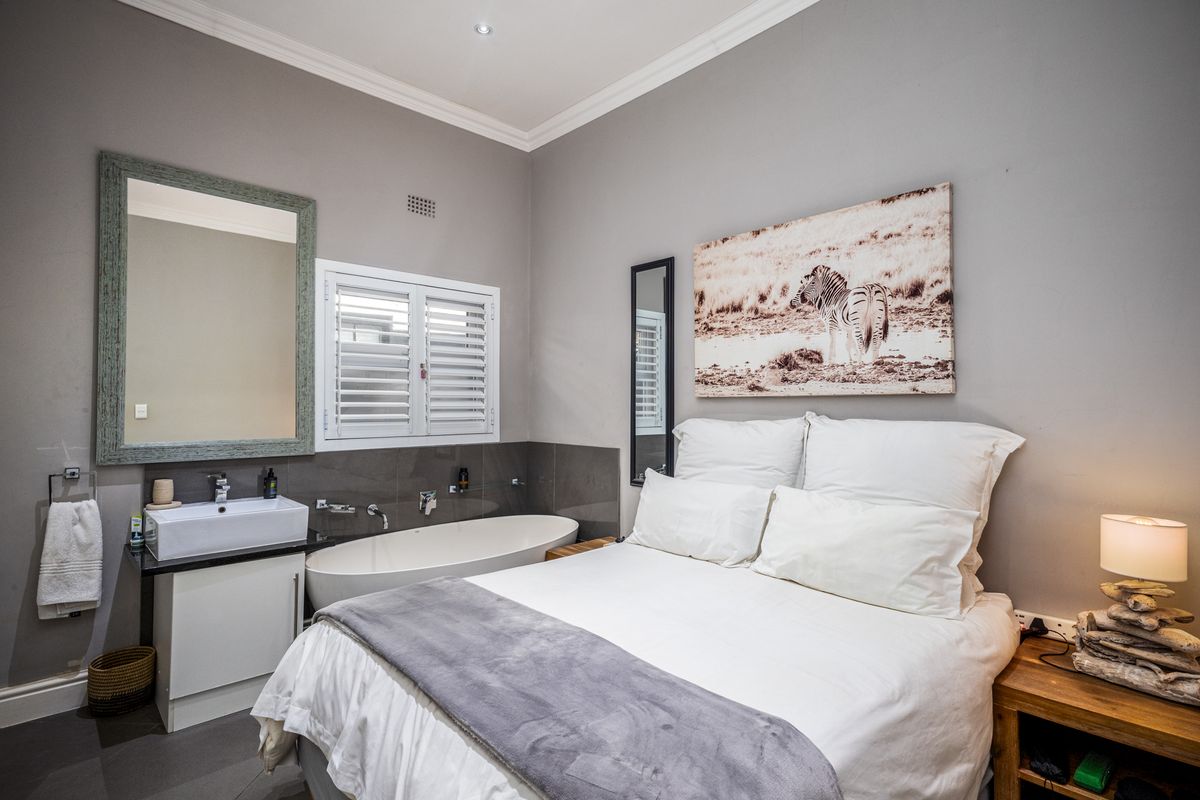 A modern bedroom featuring an integrated en-suite bathroom with a freestanding bathtub and a contemporary vessel sink vanity.