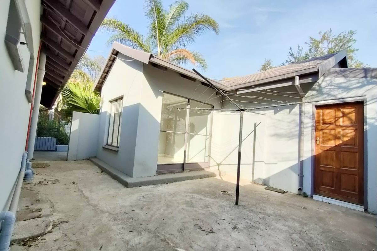 Rear exterior view of the property featuring a concrete patio area, sliding glass door access, and a solid timber door.