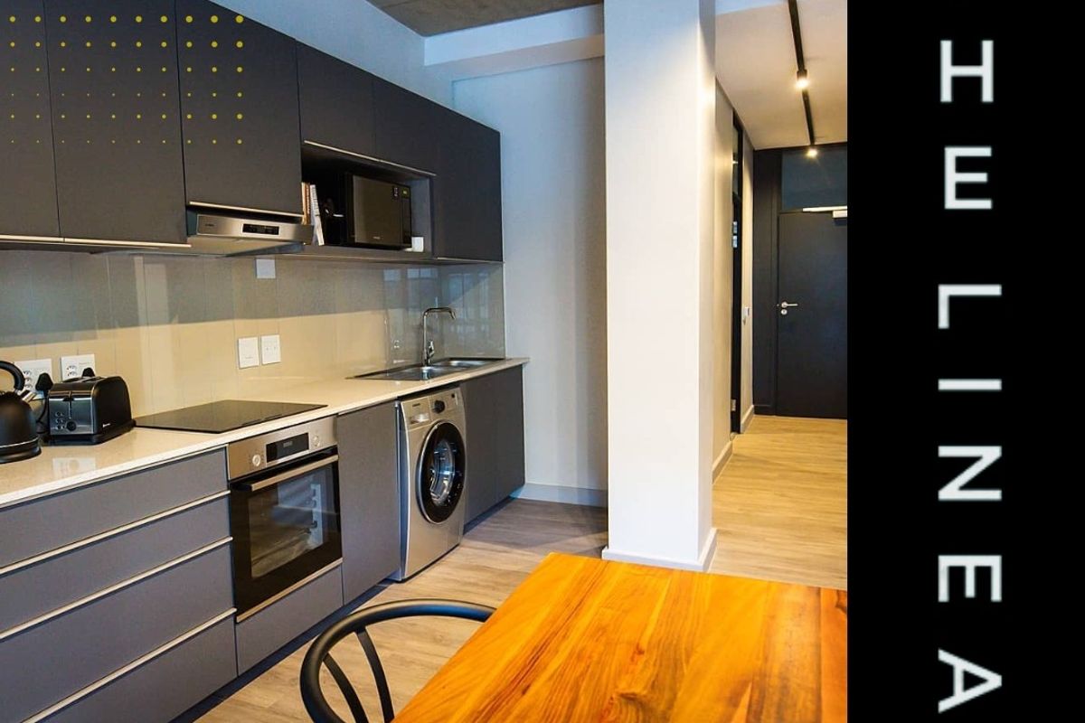 Modern kitchen featuring sleek grey cabinetry, stone countertops, integrated appliances, and an industrial-style exposed concrete ceiling.