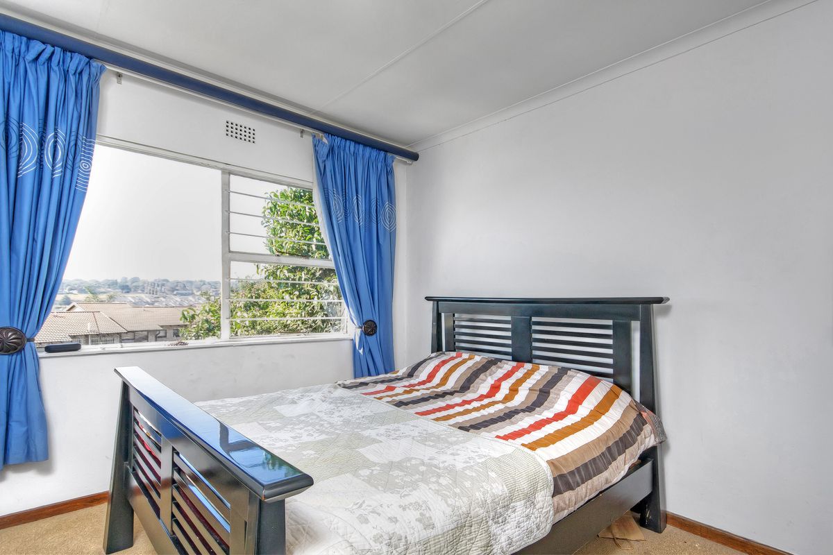 A bedroom featuring a large window with natural light, carpeted flooring, and standard ceiling finishes.