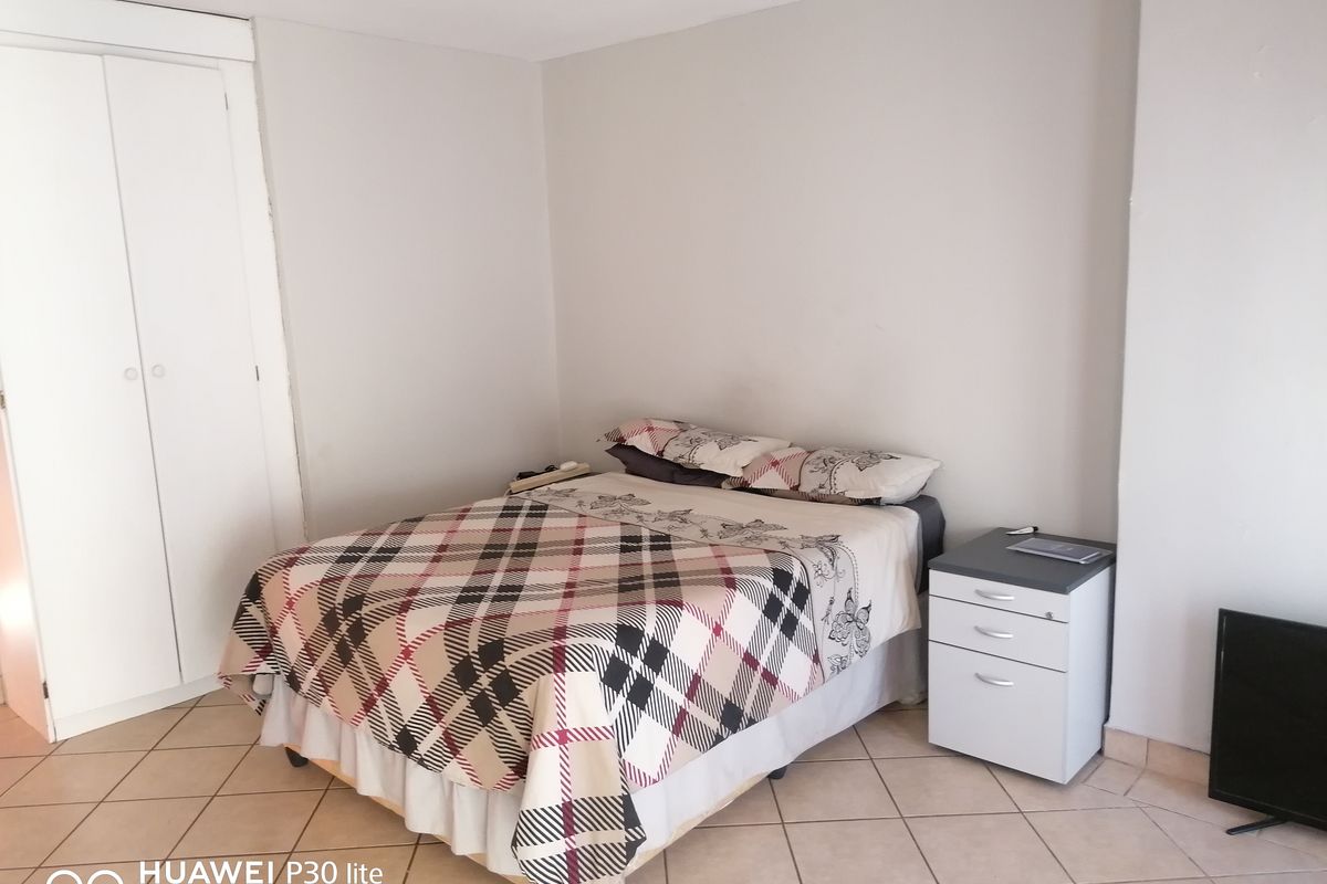 A bedroom featuring neutral wall finishes, tiled flooring, and a built-in wardrobe.
