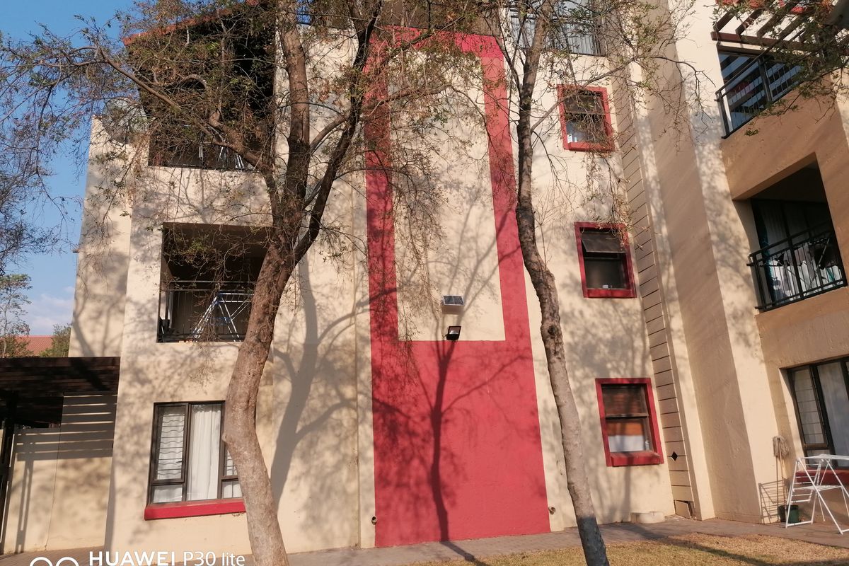 Exterior view of the apartment building facade featuring a multi-story design with balconies and red accent detailing.