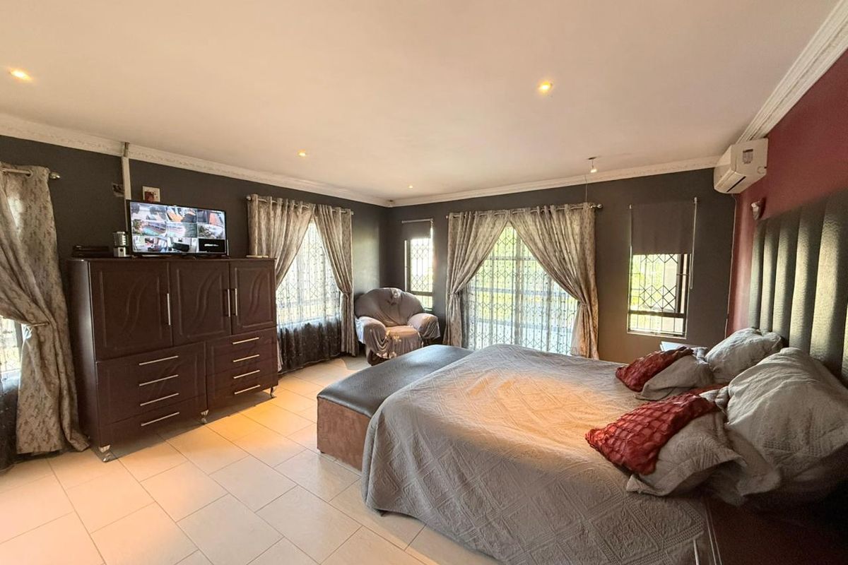 Spacious bedroom featuring tiled flooring, recessed ceiling lighting, and wall-mounted air conditioning unit.