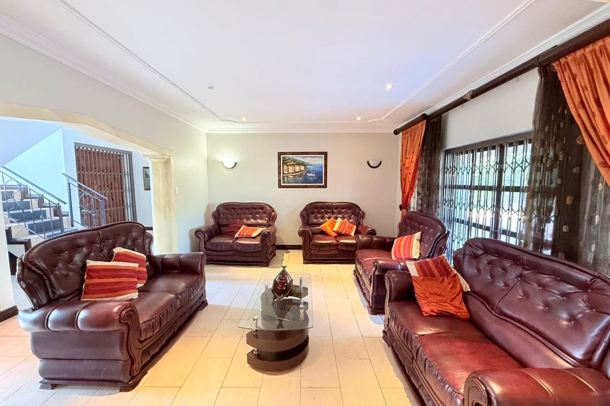 Spacious living room featuring tiled flooring, recessed ceiling lighting, and large sliding doors with security gates leading to the exterior.