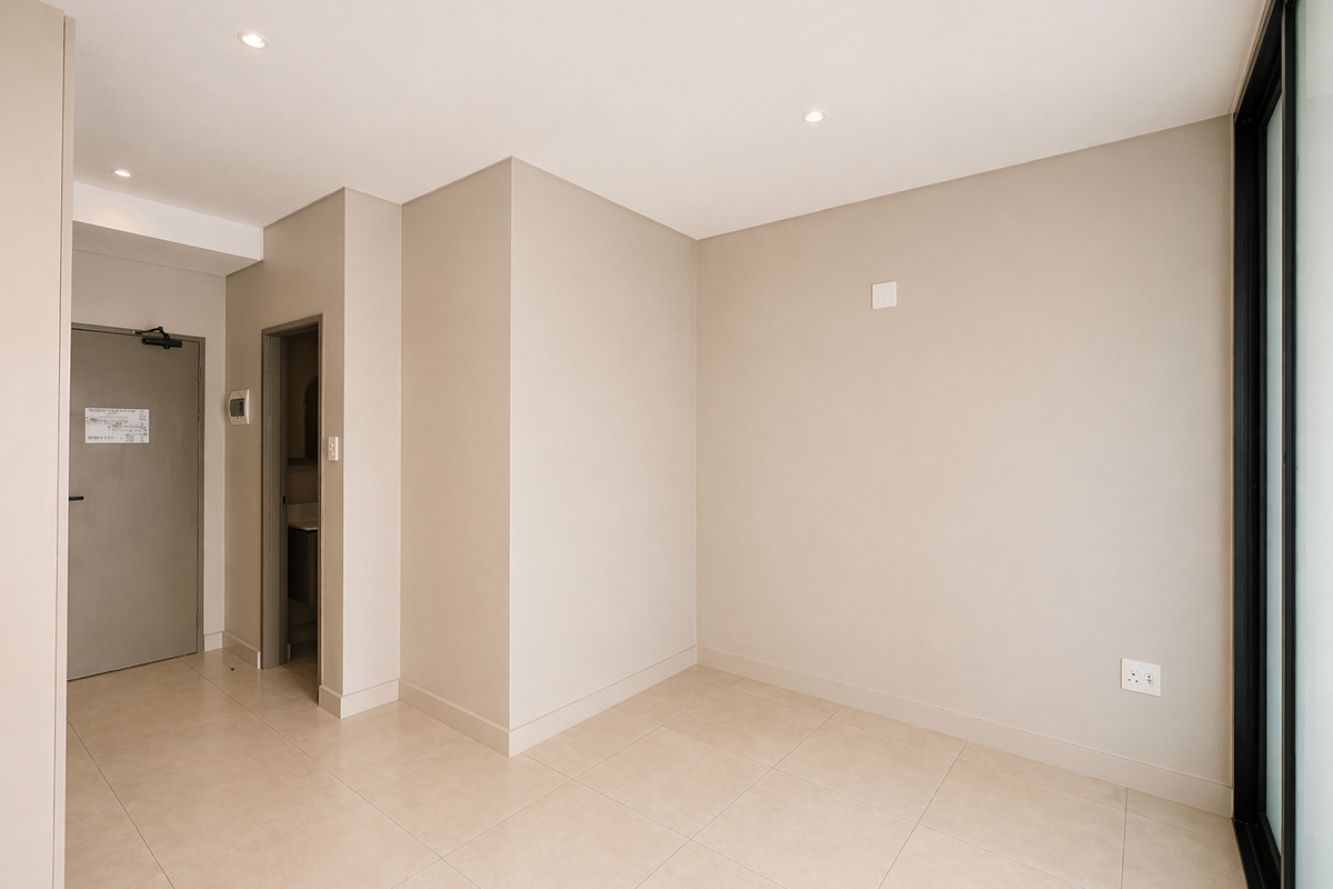 A bright, empty living area featuring neutral tiled flooring, recessed ceiling lighting, and a sliding glass door leading to an outdoor space.