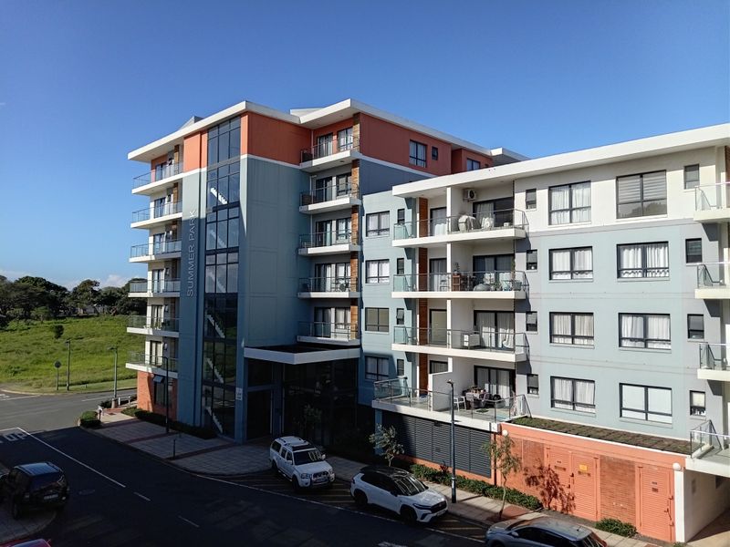 Exterior view of the Summer Park apartment complex, featuring modern multi-story architecture with balconies and glass-enclosed stairwells.