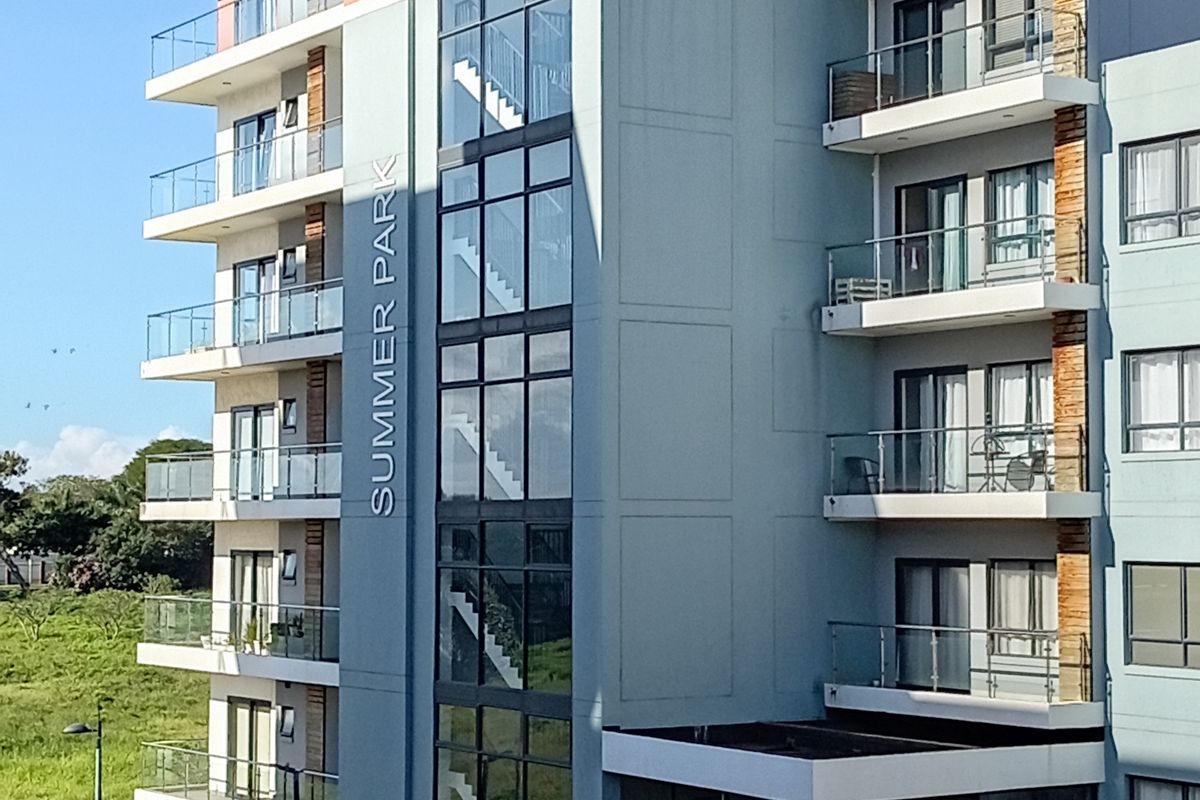 Exterior view of the Summer Park apartment building, featuring modern multi-story architecture with glass balconies and a prominent central stairwell.