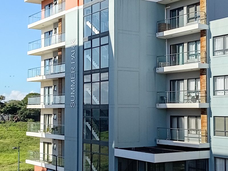 Exterior view of the Summer Park apartment building, featuring modern multi-story architecture with glass balconies and a prominent central stairwell.