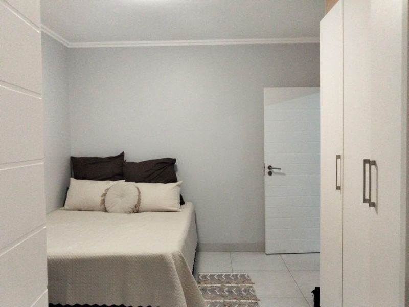 A clean and neutral bedroom featuring tiled flooring and built-in wardrobe cabinetry.