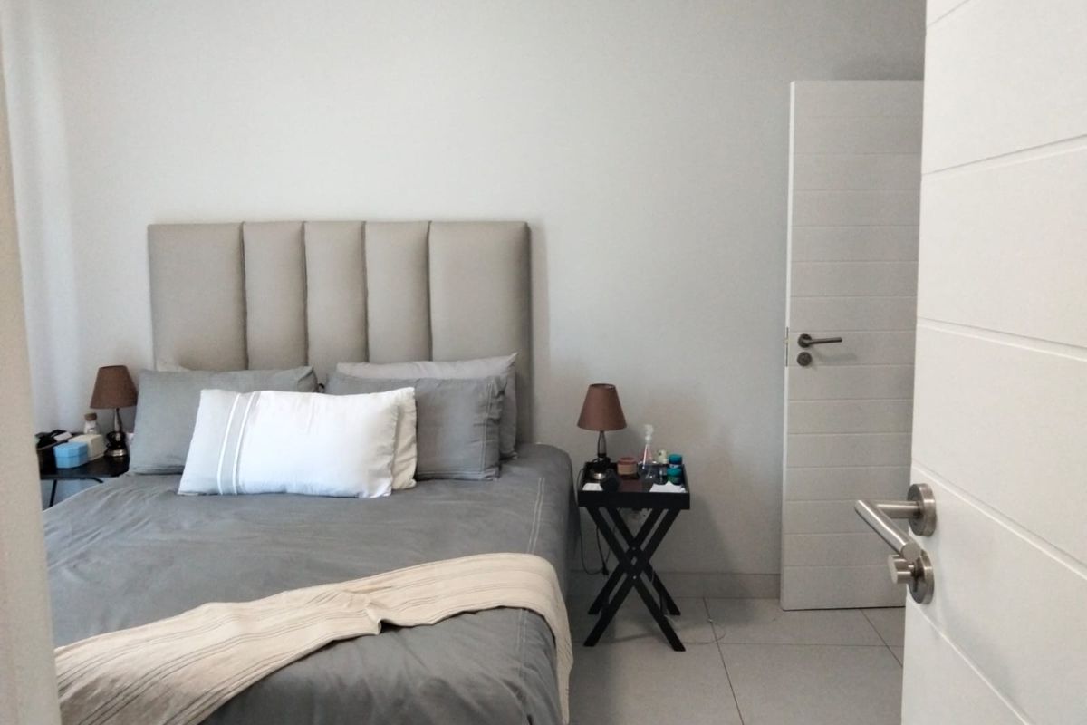 A well-maintained bedroom featuring neutral wall tones, modern tiled flooring, and a contemporary horizontal-panel interior door.