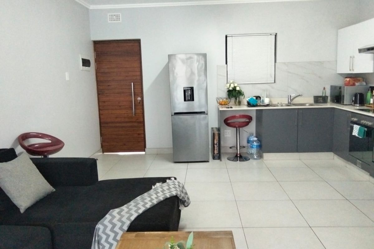 Open-plan living area featuring a modern kitchen with grey cabinetry, integrated oven, and tiled flooring throughout.