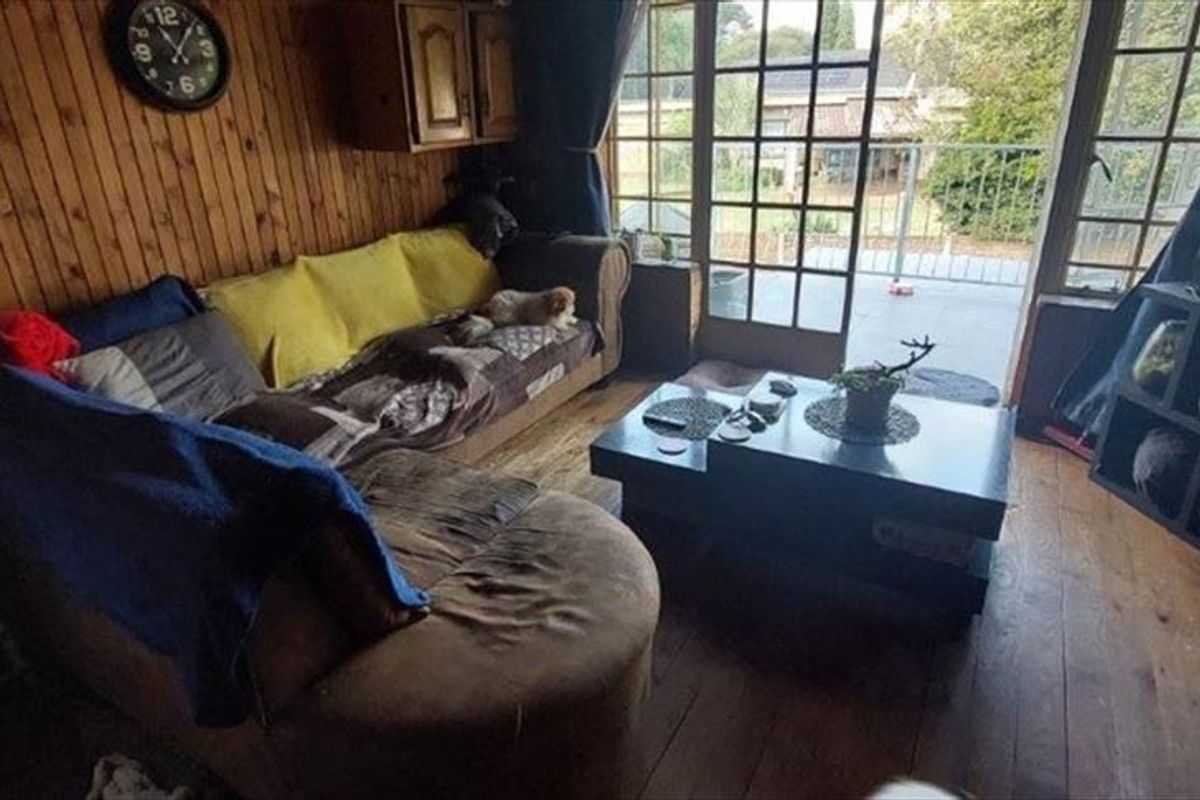A living room featuring timber wall paneling and large glass doors providing access to an outdoor balcony area.