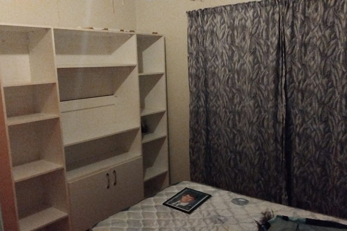 A bedroom featuring built-in shelving units and floor-to-ceiling curtains.