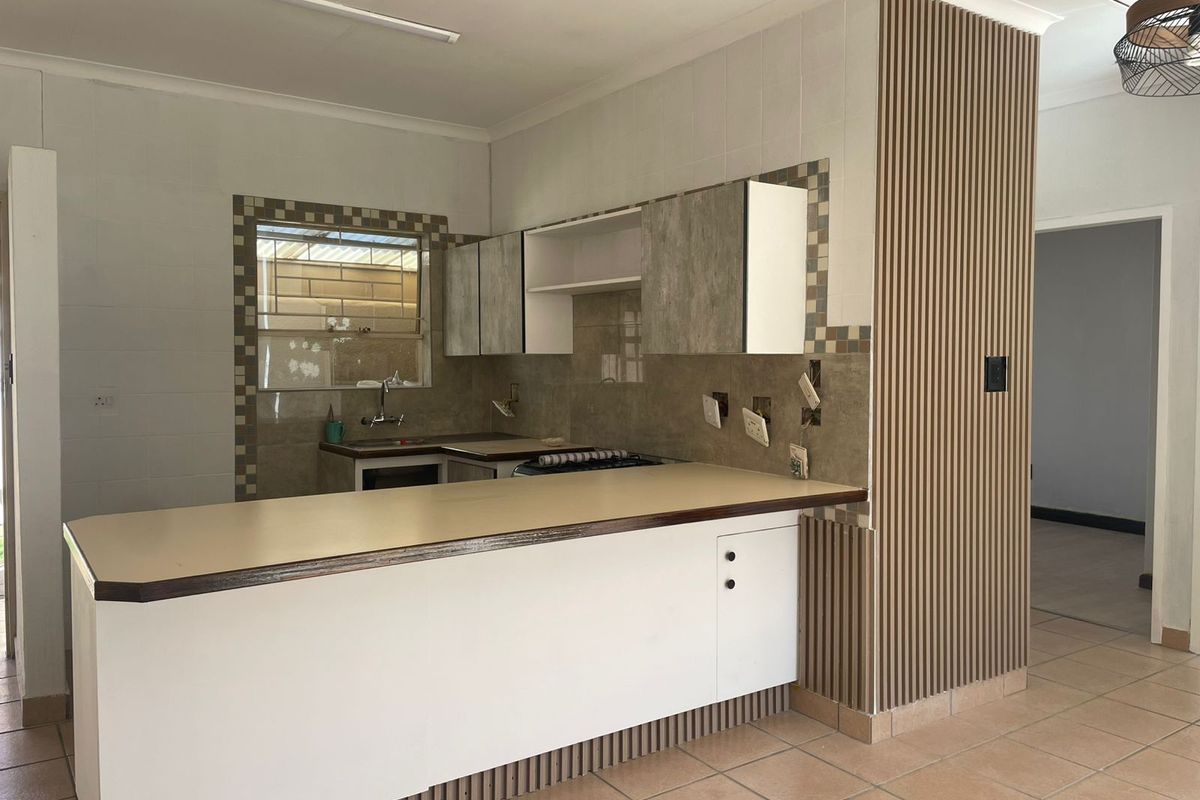Functional kitchen featuring a breakfast bar, built-in cabinetry, tiled splashbacks, and a feature slatted wall panel.