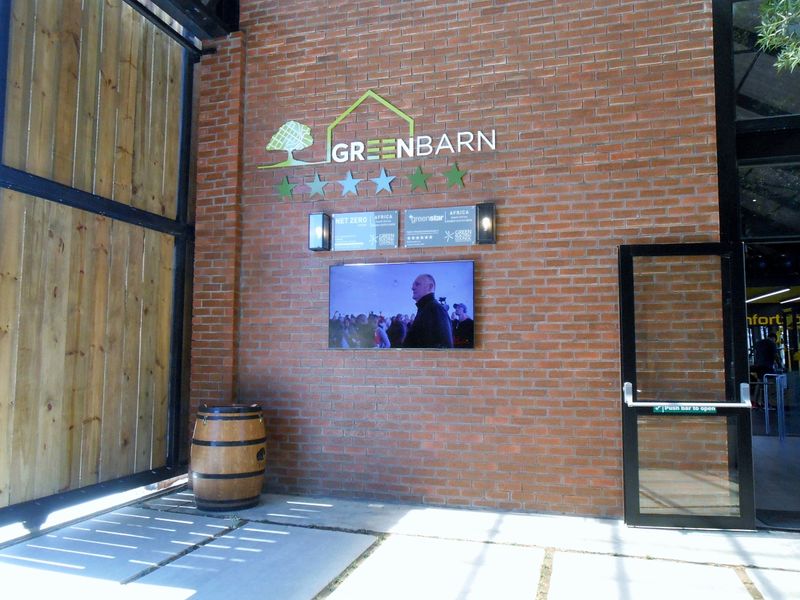 Modern entrance area featuring an exposed brick wall with professional signage, integrated display screen, and glass door access.