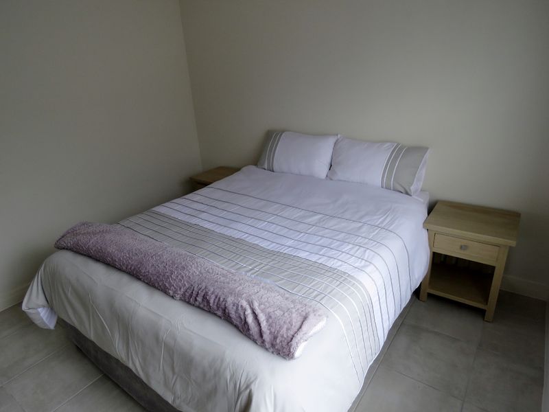 A simple bedroom featuring neutral wall tones and tiled flooring, providing a clean and functional space.