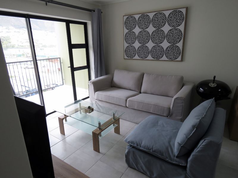 A bright living room featuring tiled flooring and a large sliding glass door providing direct access to an outdoor balcony area.