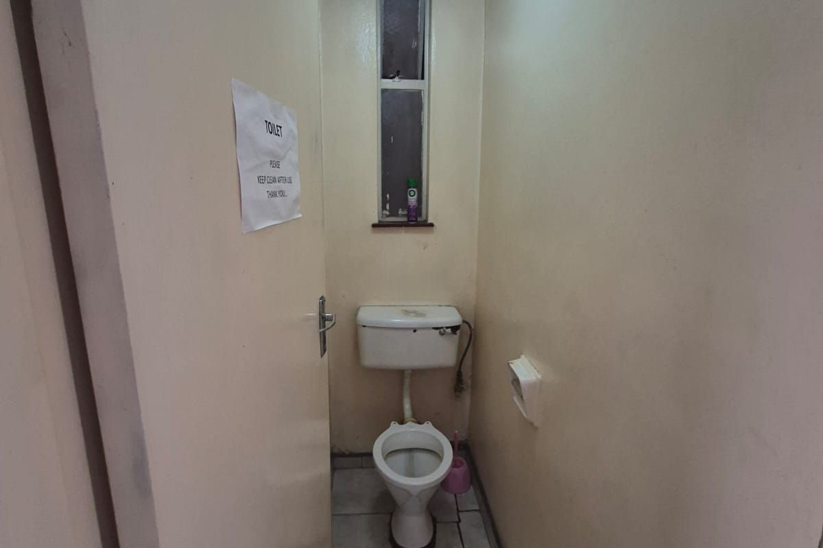 A compact, functional guest toilet featuring tiled flooring and a standard porcelain toilet suite, requiring cosmetic updates.