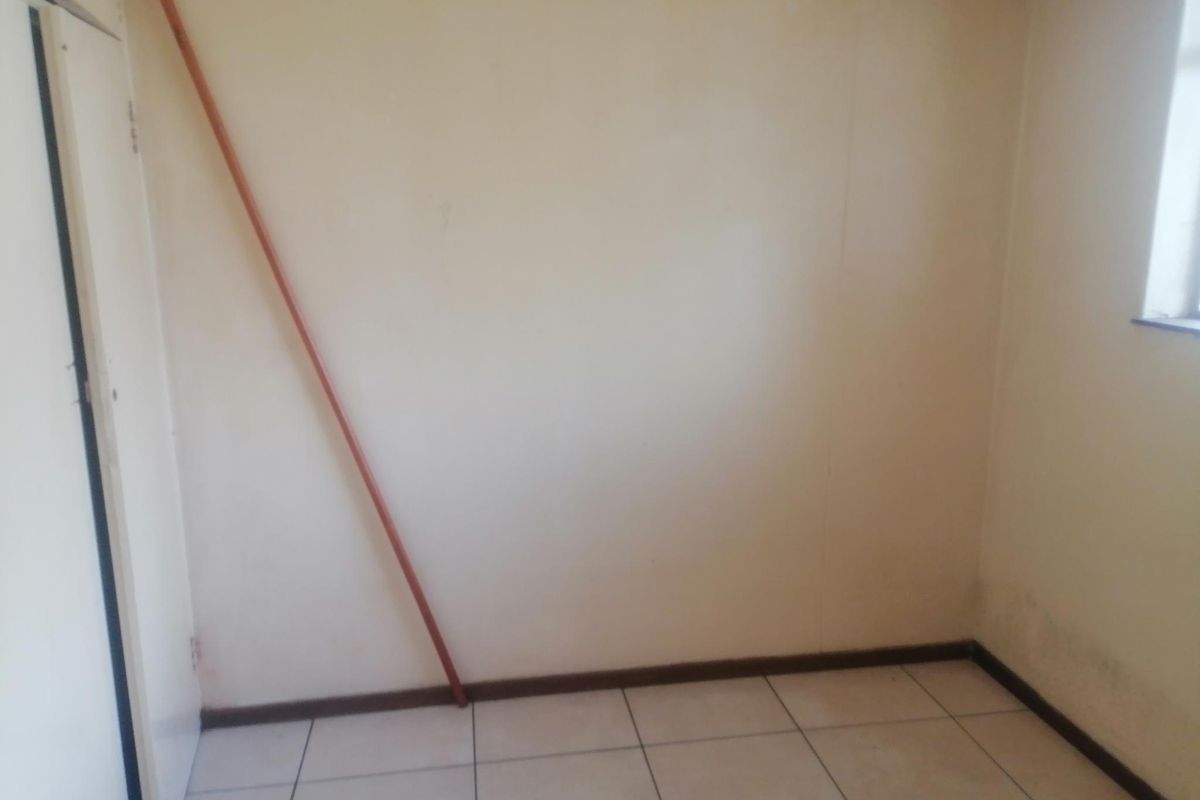 An empty bedroom featuring tiled flooring and a built-in cupboard, requiring cosmetic updates to the walls.