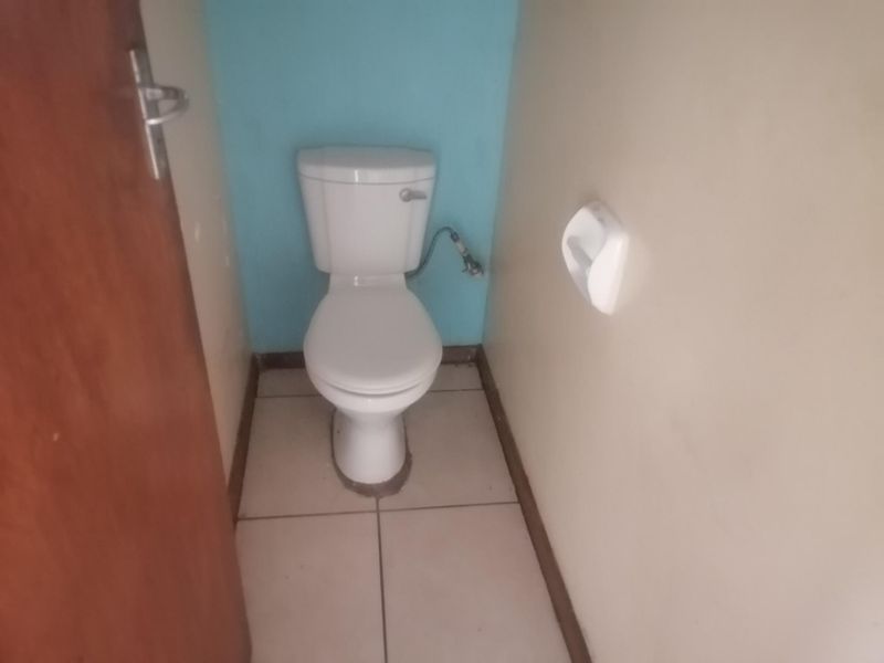 A small, basic guest toilet featuring tiled flooring and a standard white toilet suite.