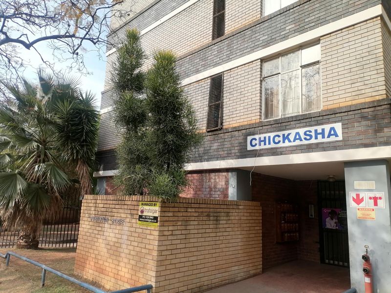 Front exterior view of the Chickasha apartment building, featuring a brick facade, secure entrance gate, and communal mailboxes.