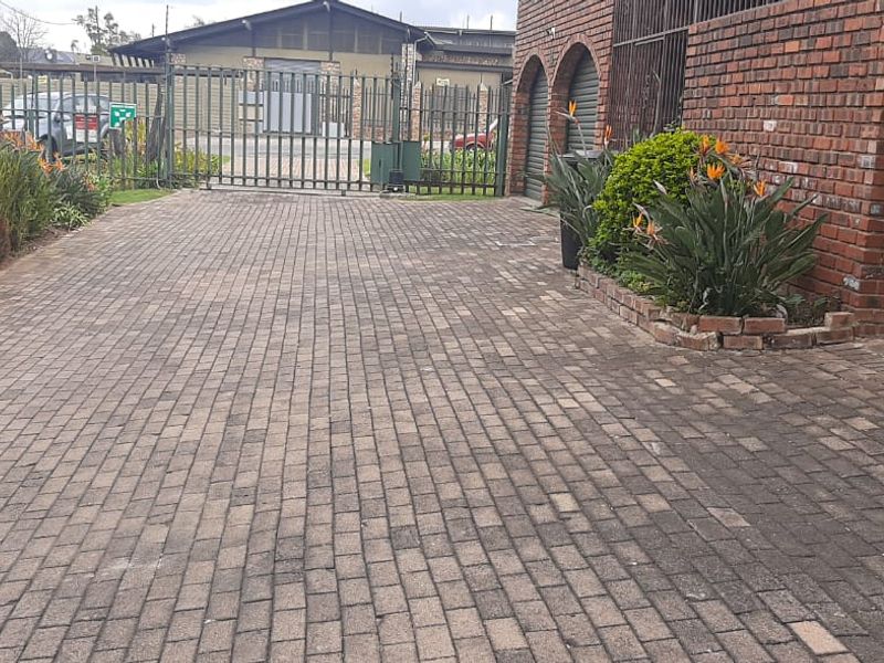 A paved driveway leading to a garage with brick facade and secure metal gate access.