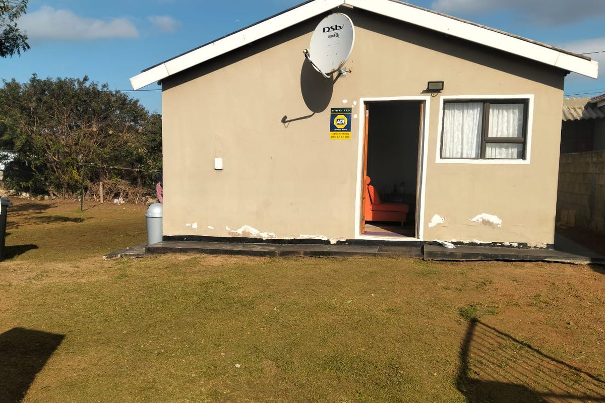 Exterior view of the rear of the house featuring a satellite dish, security signage, and a small lawn area.