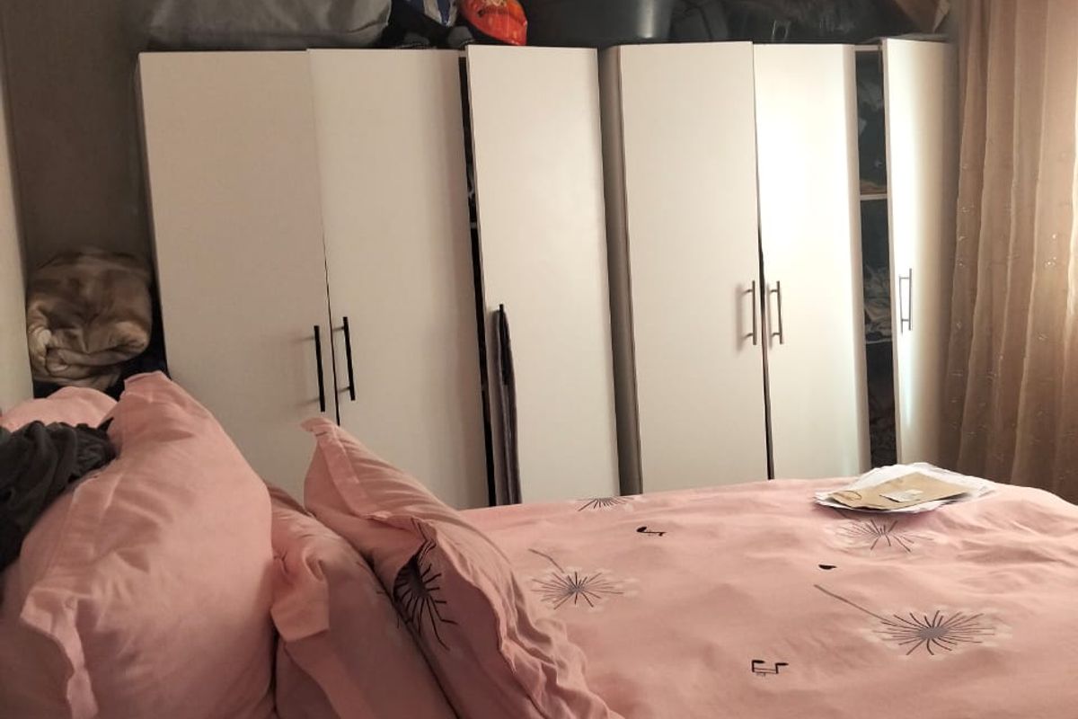 A bedroom featuring built-in white wardrobes and unfinished wall finishes, offering potential for cosmetic updates and personalization.