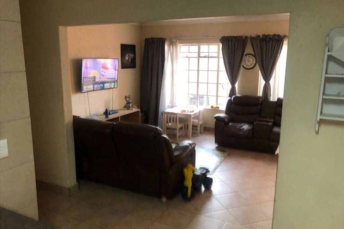 A living room area featuring tiled flooring and large windows, providing a functional space for relaxation and family activities.