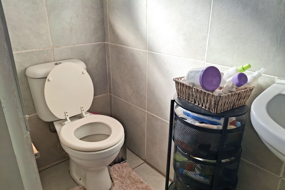 A functional bathroom featuring neutral ceramic wall and floor tiles, a standard white toilet, and a pedestal basin.