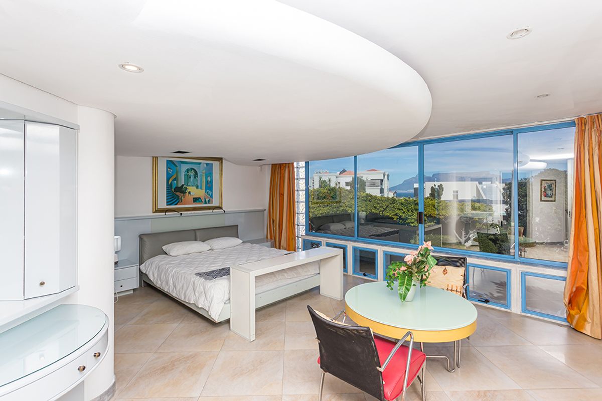Spacious bedroom featuring a unique curved ceiling design, large floor-to-ceiling windows with scenic views, and integrated storage cabinetry.