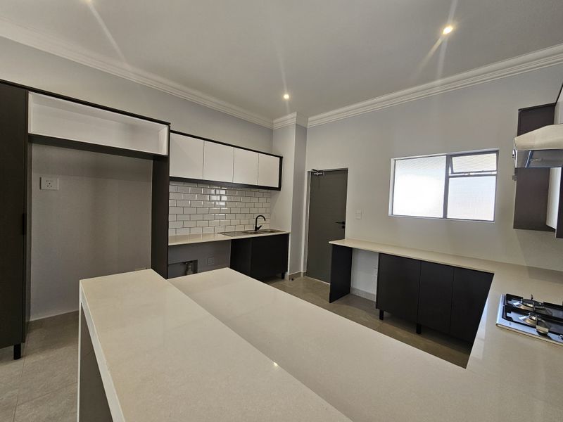 Modern kitchen featuring sleek cabinetry, stone countertops, a built-in gas hob, and a subway tile backsplash in a clean, contemporary layout.