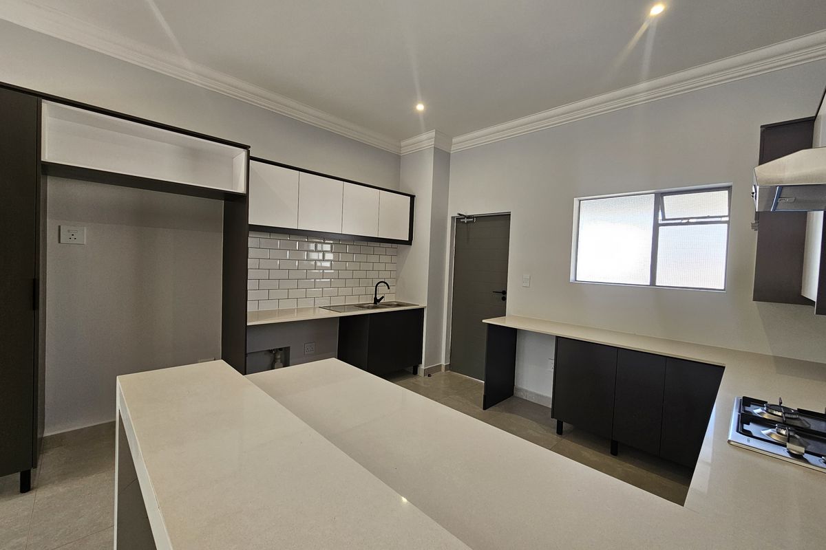 Modern kitchen featuring sleek cabinetry, stone countertops, a built-in gas hob, and a subway tile backsplash in a clean, contemporary layout.