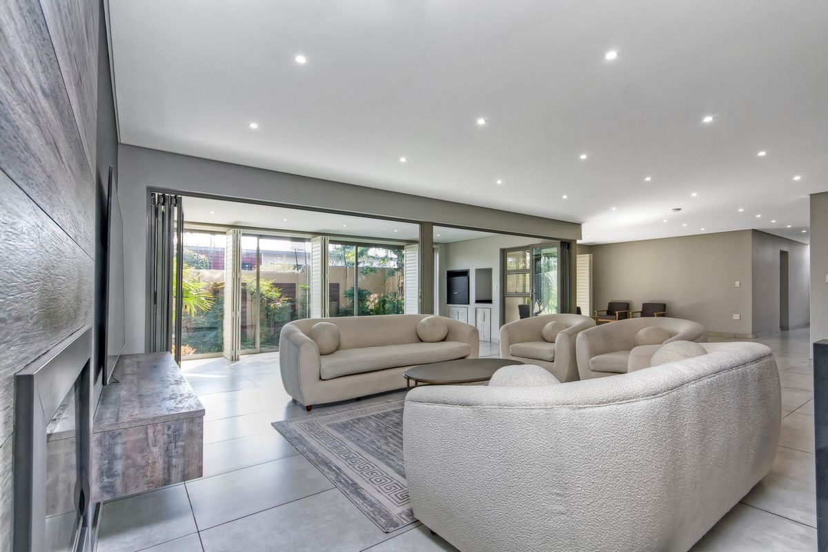 Spacious open-plan living area featuring modern tiled floors, recessed lighting, a built-in fireplace, and large stacking doors opening to the garden.