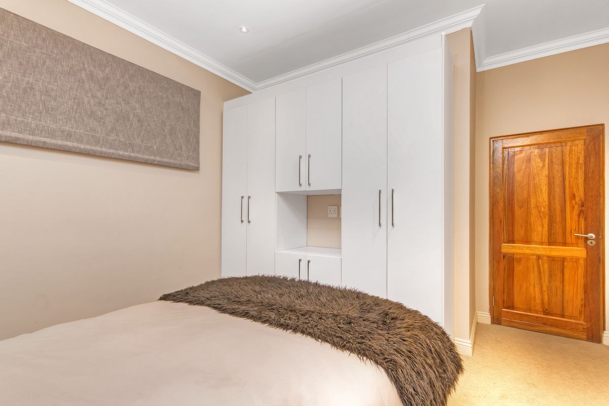 A well-maintained bedroom featuring built-in white cabinetry with integrated shelving and a solid timber door.