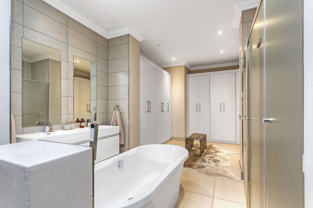 Modern bathroom featuring a freestanding bathtub, double vanity with integrated mirrors, recessed lighting, and extensive built-in cabinetry for ample storage.