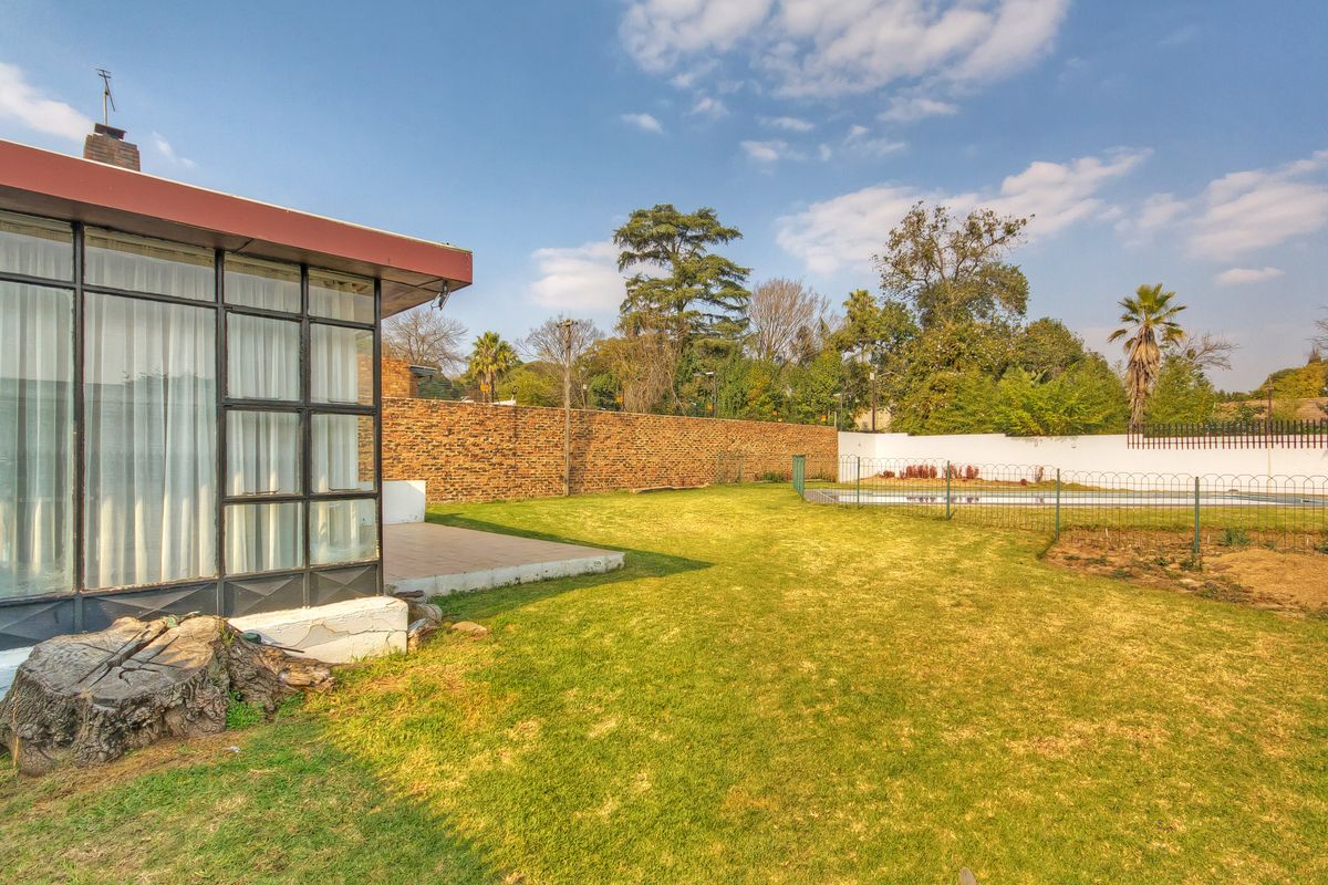 Spacious rear garden featuring a swimming pool, brick boundary walls, and a tiled patio area adjacent to the main dwelling.