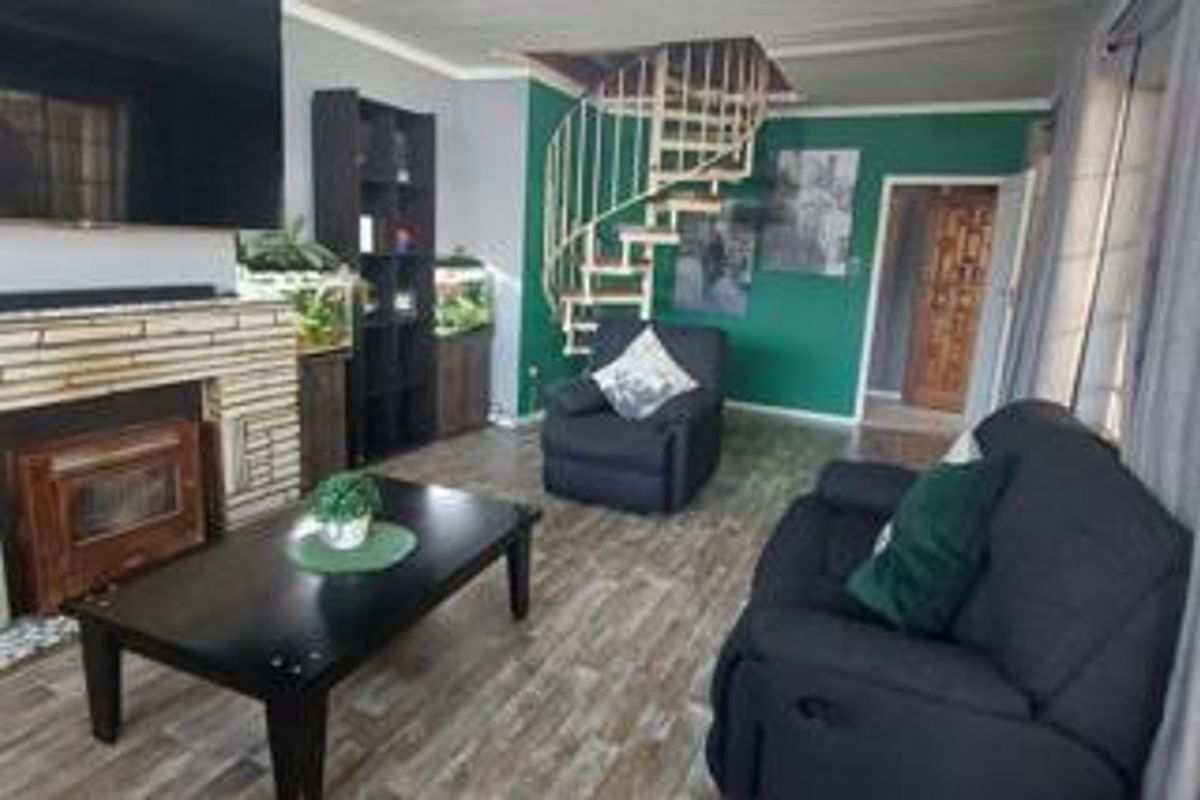 Living room featuring a stone-clad fireplace, wood-look flooring, and a distinctive spiral staircase leading to an upper level.