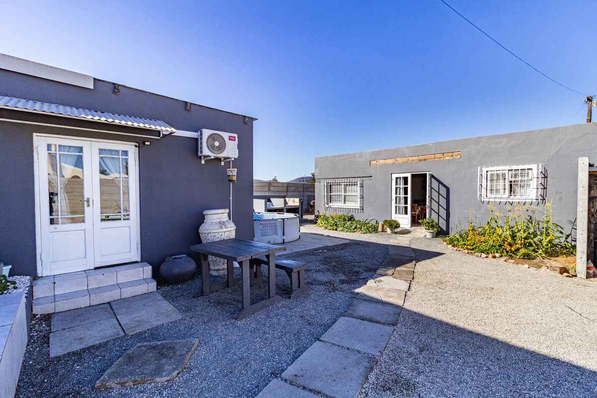 A rear courtyard area featuring gravel pathways, paved sections, and access to multiple building entrances with exterior air conditioning units.