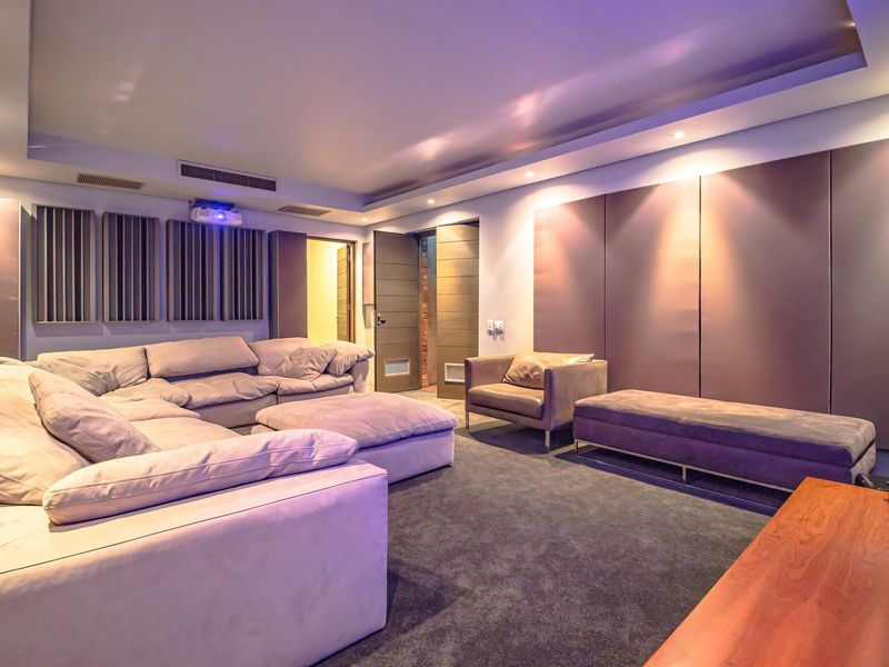 A dedicated cinema room featuring acoustic wall paneling, recessed ceiling lighting, and integrated climate control vents.