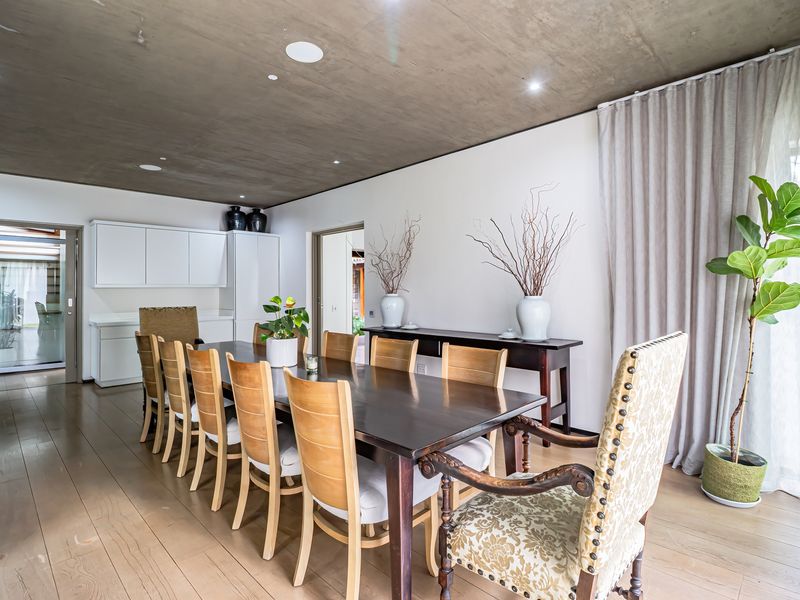 Spacious dining area featuring a modern concrete ceiling, light timber flooring, and built-in cabinetry, offering a contemporary and open atmosphere.