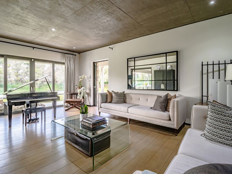 Spacious living room featuring exposed concrete ceilings, hardwood flooring, and large sliding glass doors providing seamless access to the outdoor area.