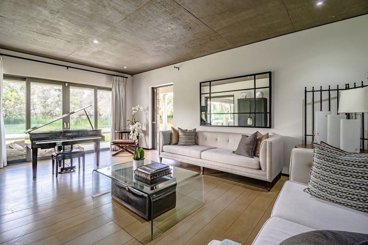 Spacious living room featuring exposed concrete ceilings, hardwood flooring, and large sliding glass doors providing seamless access to the outdoor area.
