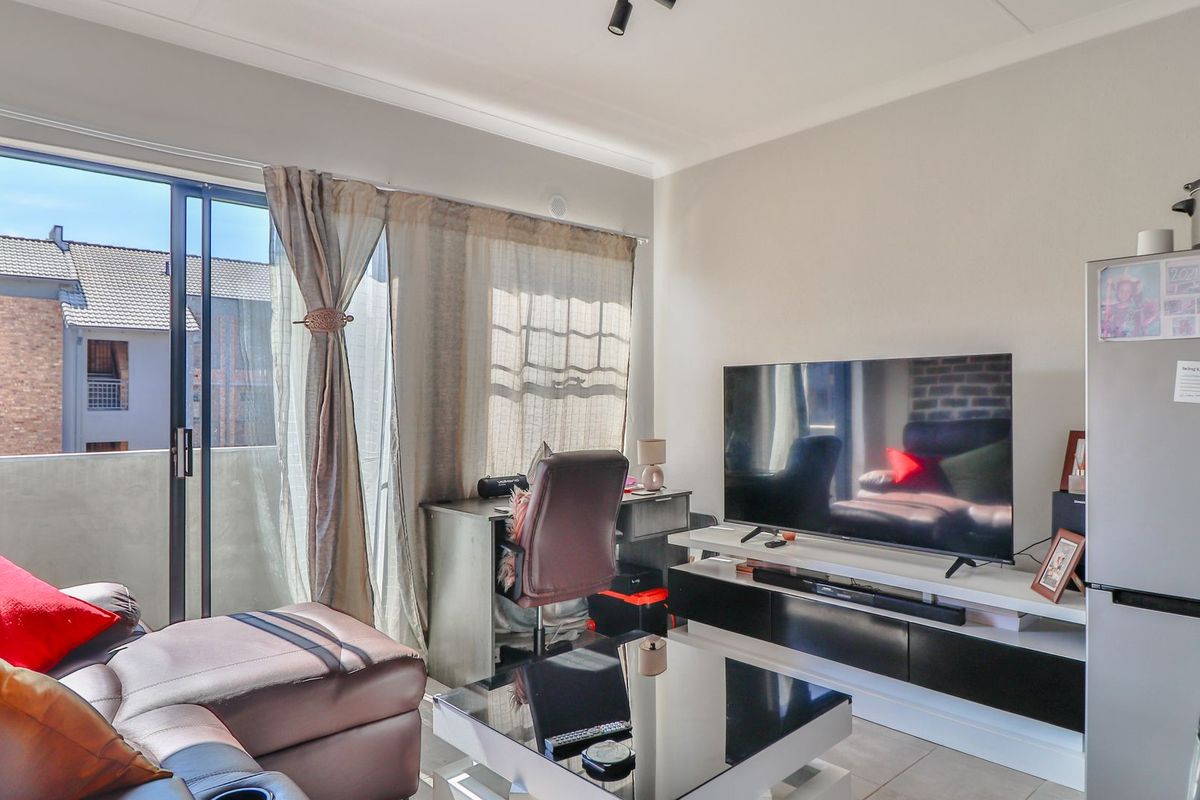 A living room featuring tiled flooring, a sliding glass door leading to a balcony, and neutral wall finishes.